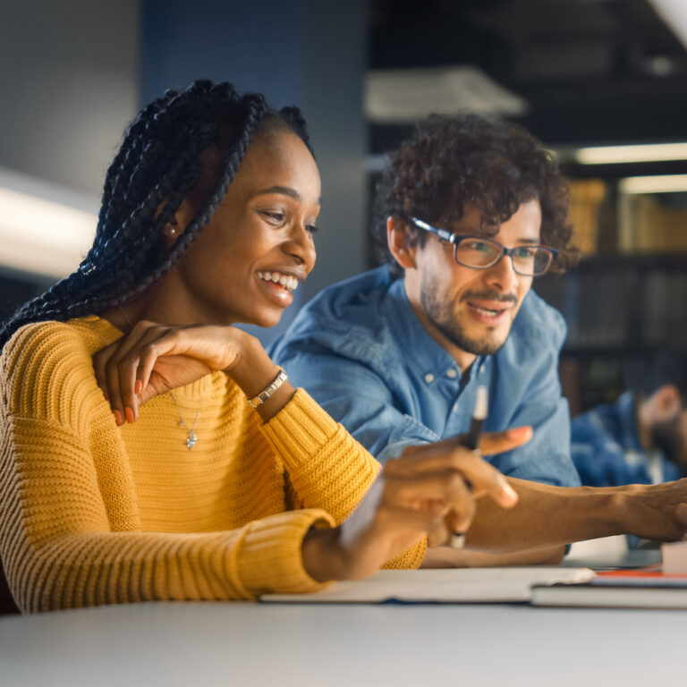 University Library: Gifted Black Girl uses Laptop, Smart Classmate Explains and Helps Her with Class Assignment. Happy Diverse Students Talking, Learning, Studying Together for Exams