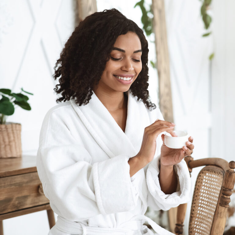 Skin Care. Beautiful Black Girl After Showering Applying Moisturising Cream On Face