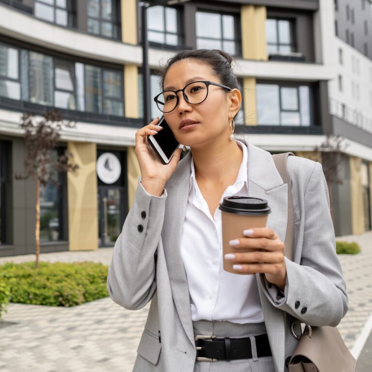 Young pretty female manager in suit phoning in the street