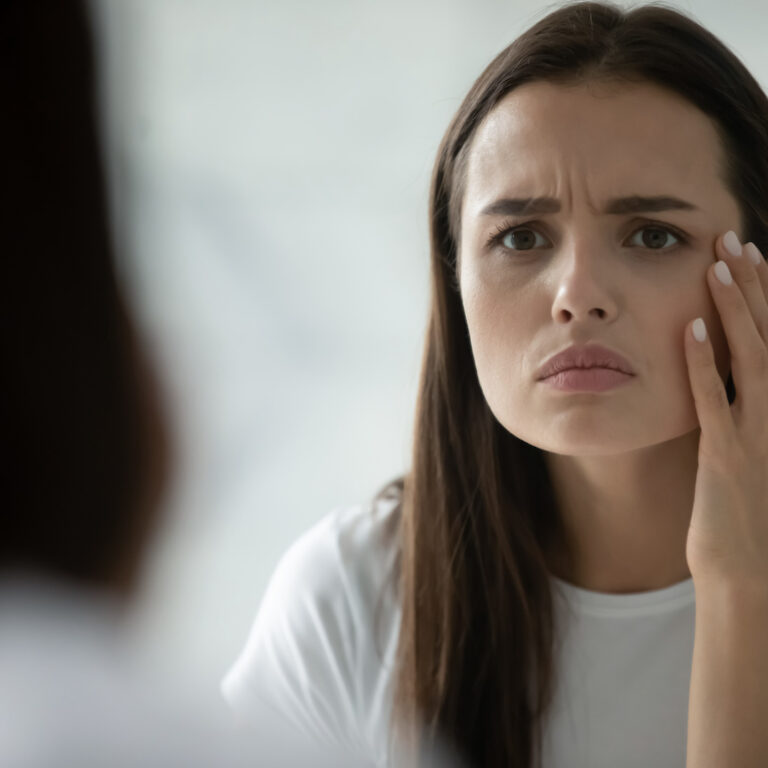Close up head shot unhappy young woman checking skin