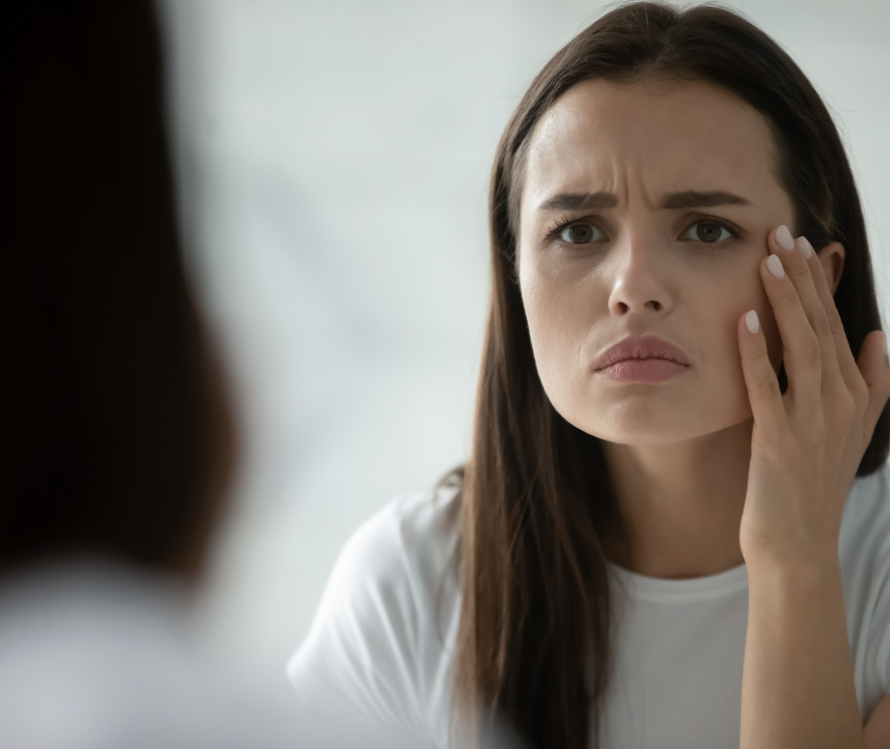 Close up head shot unhappy young woman checking skin